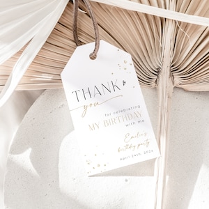 May include: White thank you tag with gold glitter accents. The tag says "Thank you for celebrating my birthday with me" and "Emilias birthday party April 24th, 202x".