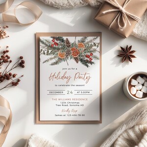 Puede incluir: Una invitación a una fiesta navideña con un diseño de acuarela de ramas de pino, bayas y rodajas de naranja. La invitación incluye el texto "Holiday Party" y los detalles del evento. Un regalo envuelto, anís estrellado y una taza de chocolate caliente también son visibles.