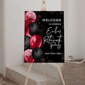 May include: A black sign on an easel with red and black balloons. The sign reads "WELCOME to celebrate Emilia's Retirement Party April 24th, 202x."