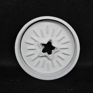 Pode incluir: Cortador de biscoitos branco e circular com um recorte em forma de estrela no centro. O cortador tem linhas radiais ao redor da estrela, criando um efeito de explosão. Ideal para assar.