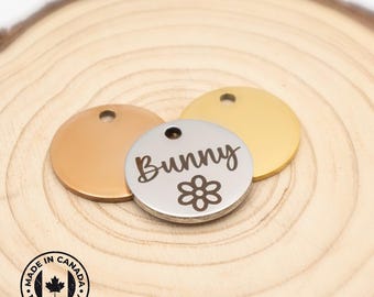 Peut inclure: Trois médailles métalliques pour animaux de compagnie en or, or rose et argent. La médaille argentée porte le mot "Bunny" en cursive avec un motif floral. Les médailles sont sur une surface en bois, avec un sceau de qualité "Made in Canada".