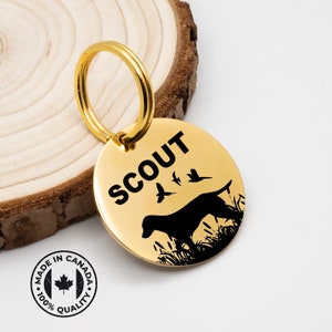 May include: Gold dog tag with a black silhouette of a dog and birds, the text "SCOUT" is engraved on the tag.