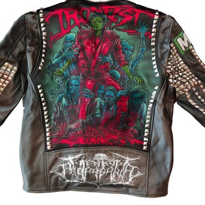 May include: Black leather jacket with silver studs and a large graphic print on the back. The print features a band name "TRAGEDY" and a band logo. The jacket has a patch on the left sleeve that says "MAYHEM".