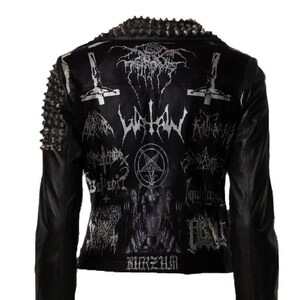 May include: Black leather jacket with silver metal studs on the shoulders and collar. The back of the jacket features various band logos and symbols in silver. The jacket has a zipper closure on the sleeves.