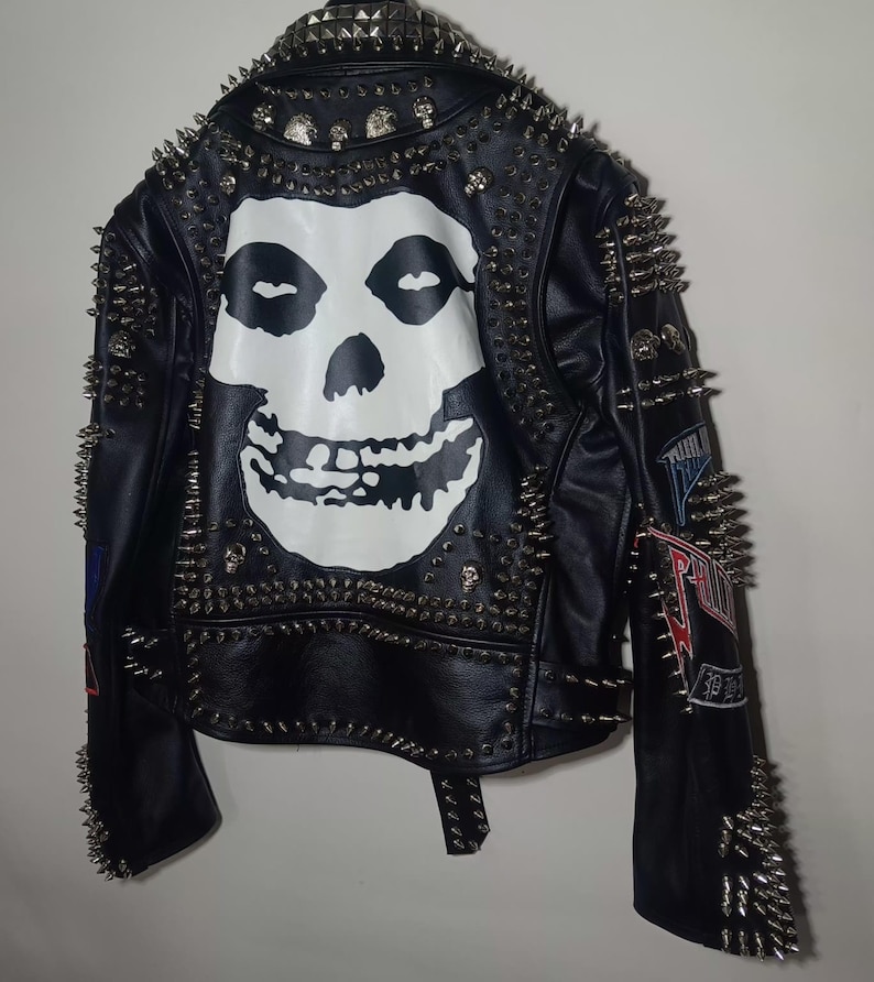 Pode incluir: Jaqueta de couro preta com tachas prateadas e um gr&aacute;fico de caveira Misfits nas costas. A jaqueta tem patches nas mangas.