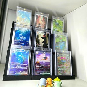 May include: A black plastic card holder with nine clear plastic card sleeves. The sleeves contain Pokemon trading cards featuring various Pokemon characters, including Wartortle, Blastoise, Charmeleon, and Gyarados. Three small Pokemon figurines are in the foreground, including a green Bulbasaur, a yellow Charmander, and a blue Squirtle.