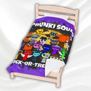 May include: A black blanket with a purple border featuring the text "PRUNKI SQUAD" and "ICK-OR-TRE". The blanket has a colorful cartoon design of various Halloween-themed characters, including a sun, robot, and pumpkin.