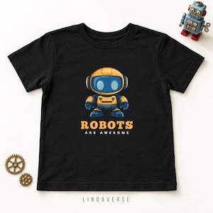 May include: A black short-sleeve t-shirt featuring a graphic of a yellow and blue robot with the text "ROBOTS ARE AWESOME" printed below it. The shirt is displayed alongside a small blue toy robot and two small brown gear-shaped embellishments.