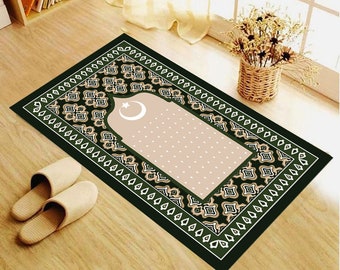 May include: A green prayer rug with a beige center featuring a crescent moon and star design. The rug has a decorative border with a repeating pattern.
