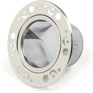 May include: A stainless steel tea infuser with a mesh basket. The infuser features a decorative ring with cut-out crescent moon and star shapes. The infuser is designed for steeping loose leaf tea.