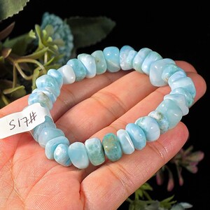 Puede incluir: Una pulsera el&aacute;stica compuesta por cuentas de piedra pulidas e irregulares de color azul claro y turquesa. La pulsera presenta una peque&ntilde;a etiqueta rectangular blanca con el texto escrito a mano #15 unido al lado de la hebra de cuentas.