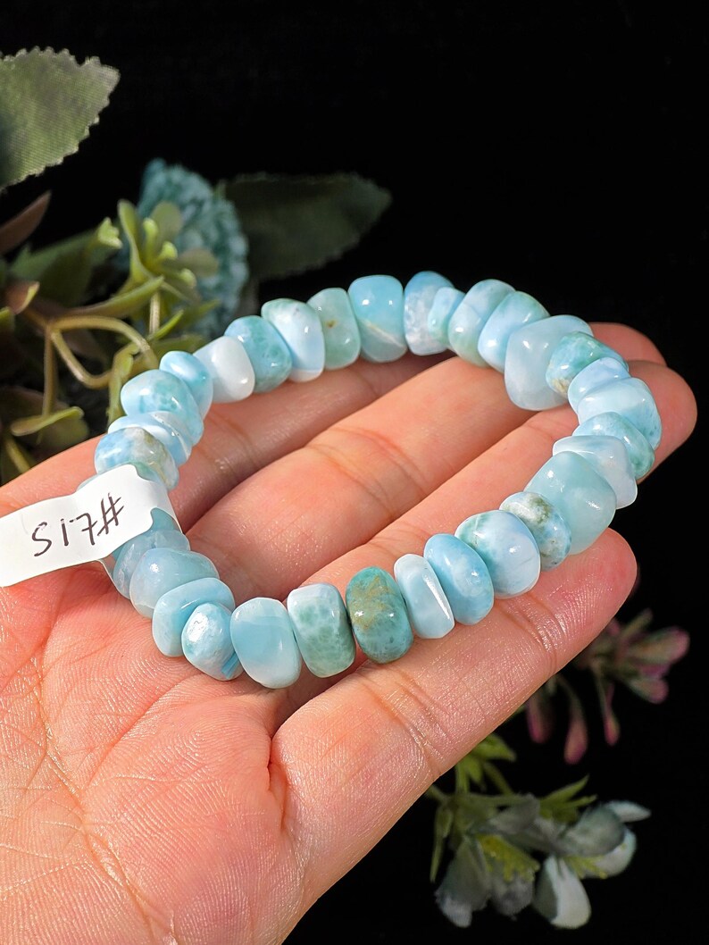 Puede incluir: Una pulsera el&aacute;stica compuesta por cuentas de piedra pulidas e irregulares de color azul claro y turquesa. La pulsera presenta una peque&ntilde;a etiqueta rectangular blanca con el texto escrito a mano #15 unido al lado de la hebra de cuentas.