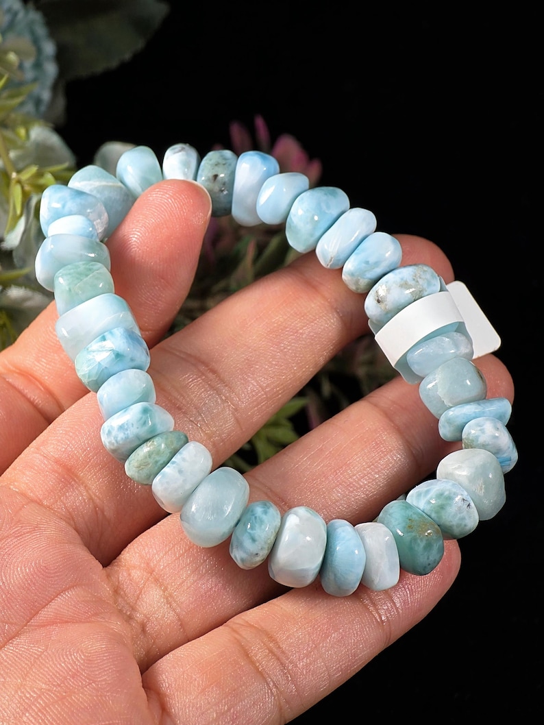 Puede incluir: Una pulsera el&aacute;stica compuesta por numerosas cuentas de Larimar pulidas y rodadas en tonos variados de azul cielo, turquesa y blanco. Las cuentas son redondeadas e irregulares, ensartadas en un cord&oacute;n el&aacute;stico y cuentan con una peque&ntilde;a etiqueta blanca.