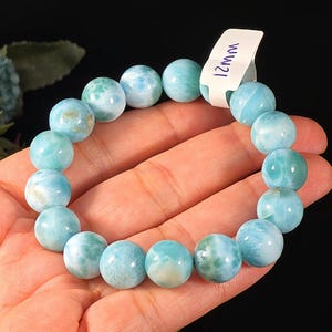 May include: A stretch bracelet composed of round, polished light blue and white marbled beads. A small white rectangular tag is attached to the bracelet, featuring the handwritten text 12mm, indicating the bead diameter in millimetres.