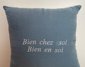 Coussin en lin au message brodé "bien chez soi, bien en soi". Il a l'originalité d'être bicolore et sa housse est lavable en machine à 30C.