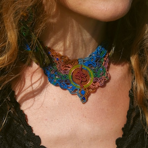May include: A colorful crocheted necklace with a multi-colored design. The necklace is made of yarn and has a intricate pattern.