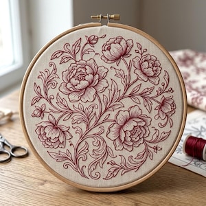 Peut inclure: Un tambour à broder circulaire en bois contenant un tissu beige clair. Le tissu présente un motif floral détaillé brodé avec du fil rouge foncé, représentant plusieurs pivoines en fleurs avec des feuilles complexes et des tiges en volutes.