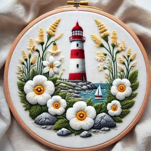 May include: Embroidered hoop art featuring a red and white lighthouse with a sailboat in the water, surrounded by white flowers and green foliage.