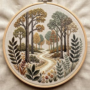 May include: A circular embroidery hoop containing a fabric panel with a detailed thread-stitched landscape. The scene features a winding path leading through a forest of trees in shades of green, brown, and gold, surrounded by foliage.
