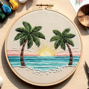 Puede incluir: Escena de paisaje bordada en un aro de madera. El diseño presenta dos palmeras, un sol poniente y olas del océano en tonos verdes, azules, amarillos y rosas. Cuentas blancas representan la arena. El aro está rodeado de tela beige.