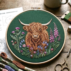 May include: An embroidered Highland cow on a green background, framed in a wooden hoop. The embroidery includes detailed brown fur and colourful flowers. The kit includes a pattern and threads for the project.
