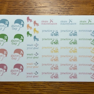 May include: A sheet of colorful stickers with various designs, including roller skates, hockey helmets, and text such as "game day", "practice", "scrimmage", "wash your gear", and "skate maintenance".
