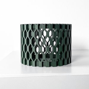 May include: A dark green cylindrical planter with a hexagonal pattern. The planter is made of a sturdy material and has a modern design.