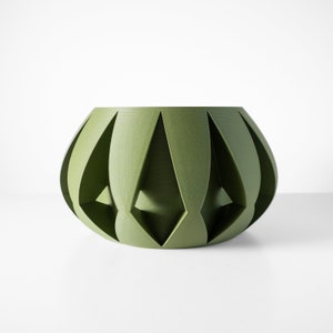 May include: A green ceramic planter with a geometric design. The planter has a rounded shape and is made of a textured material.