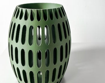 May include: A green, round, decorative planter with a geometric pattern of oval cutouts. The planter is made of a smooth, textured material.