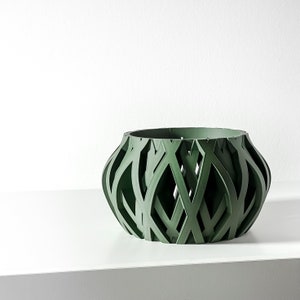 May include: A green woven planter with a geometric design. The planter is made of a lightweight material and has a wide, open top.