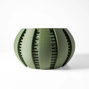 May include: A green, round planter with a geometric design. The planter has a series of vertical and horizontal lines that create a grid pattern.