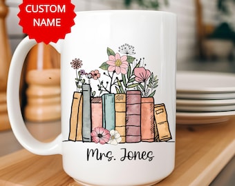 May include: White ceramic mug with a design of a stack of books with flowers on top. The text "Mrs. Jones" is printed on the mug.