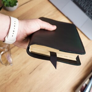May include: A black leather-bound journal with a bookmark. The journal is closed and has a plain cover.