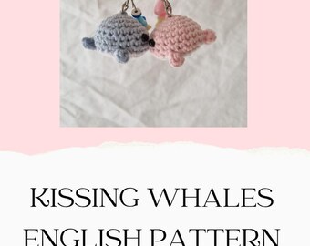 May include: Two handmade crochet whale keyrings, one light blue and one pink, are shown kissing. The keyrings are attached to silver keyrings. The text "KISSING WHALES ENGLISH PATTERN" is displayed below the keyrings.