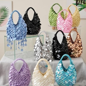 Pode incluir: Uma coleção de pequenas bolsas com alça redonda cobertas por lantejoulas circulares sobrepostas em várias cores, incluindo azul claro, preto, rosa, prata, bronze, lavanda, creme e turquesa, algumas com lantejoulas pendentes como detalhe.