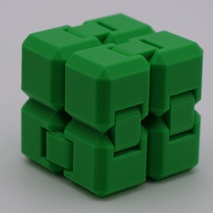 May include: A green 3D printed puzzle cube with a unique interlocking design. The cube is made of multiple smaller cubes that can be rotated and manipulated.