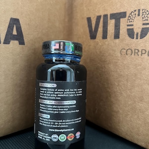 May include: A black bottle with a blue lid and a white label. The label has the text "AMINOPLEX" and information about the product, including dosage and administration instructions. The bottle is labeled as a product of Biovet Pharma, Miami, FL, USA.