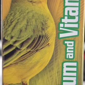 May include: A product label for a liquid supplement for veterinary use. The label features a yellow bird illustration and text that reads "Calcium and Vitamin D". The product contains 60ml and is for strong bones and eggshell.