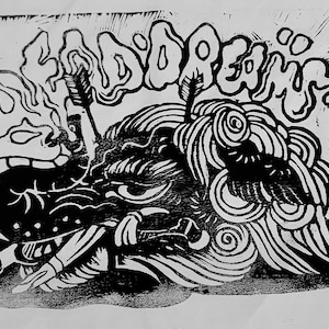 以下が含まれることがあります： 黒と白の版画で、大きな頭と渦巻く髪を持つ生き物が描かれている。生き物は煙に囲まれており、"D.D.REAM"という単語がスタイリッシュなフォントで書かれている。