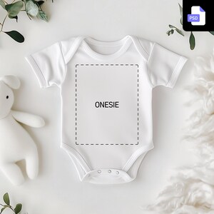以下が含まれることがあります： カスタマイズ用の空白エリアのある白いロンパース。ロンパースには「ONESIE」というテキストラベルが付いています。