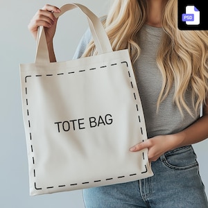 Könnte beinhalten: Eine weiße Canvas-Tragetasche mit schwarzen Nähten und dem aufgedruckten Text "TOTE BAG" in Schwarz.