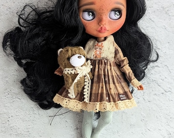 May include: A custom art doll with black hair and freckles, wearing a brown plaid dress with lace trim, holding a small teddy bear. The doll has large eyes and is wearing light green tights.