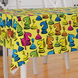 May include: Yellow tablecloth with a colorful chess piece pattern. The tablecloth features a repeating pattern of colorful chess pieces, including knights, pawns, and rooks.