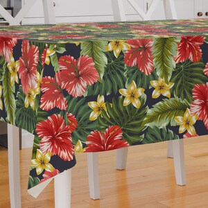 May include: A dark blue tablecloth with a tropical print featuring red hibiscus flowers, yellow plumeria flowers, and green leaves.