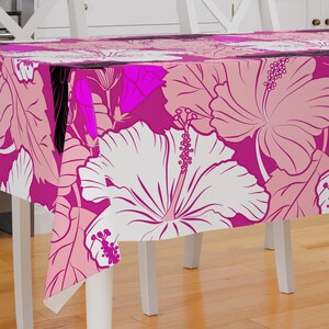 May include: Pink and white floral tablecloth with a hibiscus pattern. The tablecloth is made of a soft, durable fabric and is perfect for adding a touch of tropical elegance to any dining table.