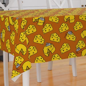 May include: A brown tablecloth with a repeating pattern of yellow cheese wedges and mice. The cheese wedges are outlined in black and have small holes. The mice are gray and have black eyes and whiskers.