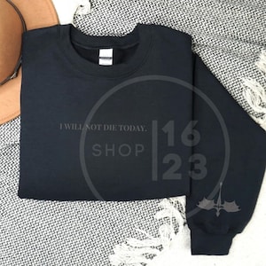 May include: Black sweatshirt with the text "I will not die today. Shop 1623" printed on the front.