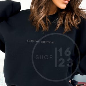 May include: Black sweatshirt with the text "I will not die today." and the logo "Shop 1623" printed on the front.