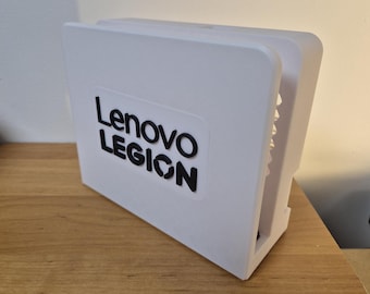 May include: A white Lenovo Legion gaming console case with black lettering. The case is rectangular with a slot on the side. The case is sitting on a wooden surface.