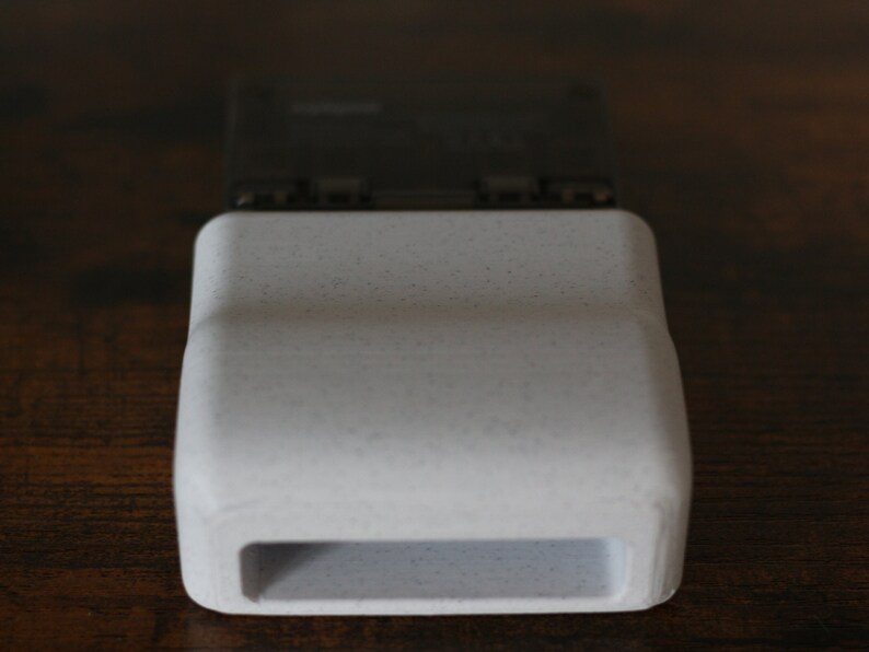 May include: A white plastic case with a rectangular opening. The case is designed to hold a small electronic device.